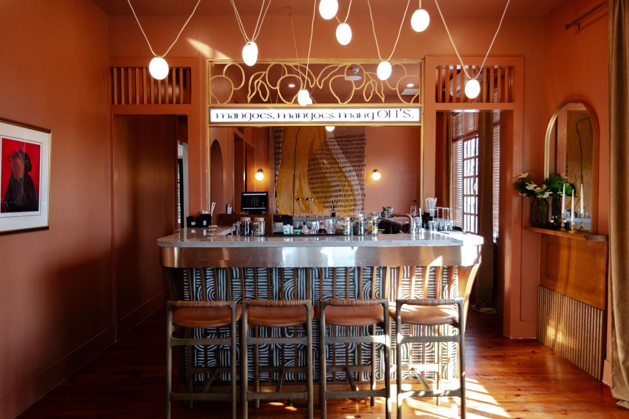 The marble-topped bar at Olive House under its mangoes sign